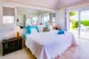 Bright villa bedroom with king bed, terrace access, and garden views in a St Barts vacation rental.