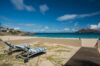 Two striped sun loungers on sandy terrace facing the turquoise sea and small island in the distance.