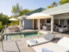 Sunlit villa terrace with loungers, umbrellas, and private pool beside open-air living spaces in a St Barts vacation rental.