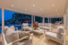 Covered outdoor lounge with modern sofas and pool view at dusk in a luxury St Barts villa rental.