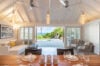 Open-concept living and dining area in a St Barts villa with ocean views through wide terrace doors.