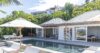 Elegant St Barts villa with pool terrace, shaded loungers, and tropical hillside backdrop.