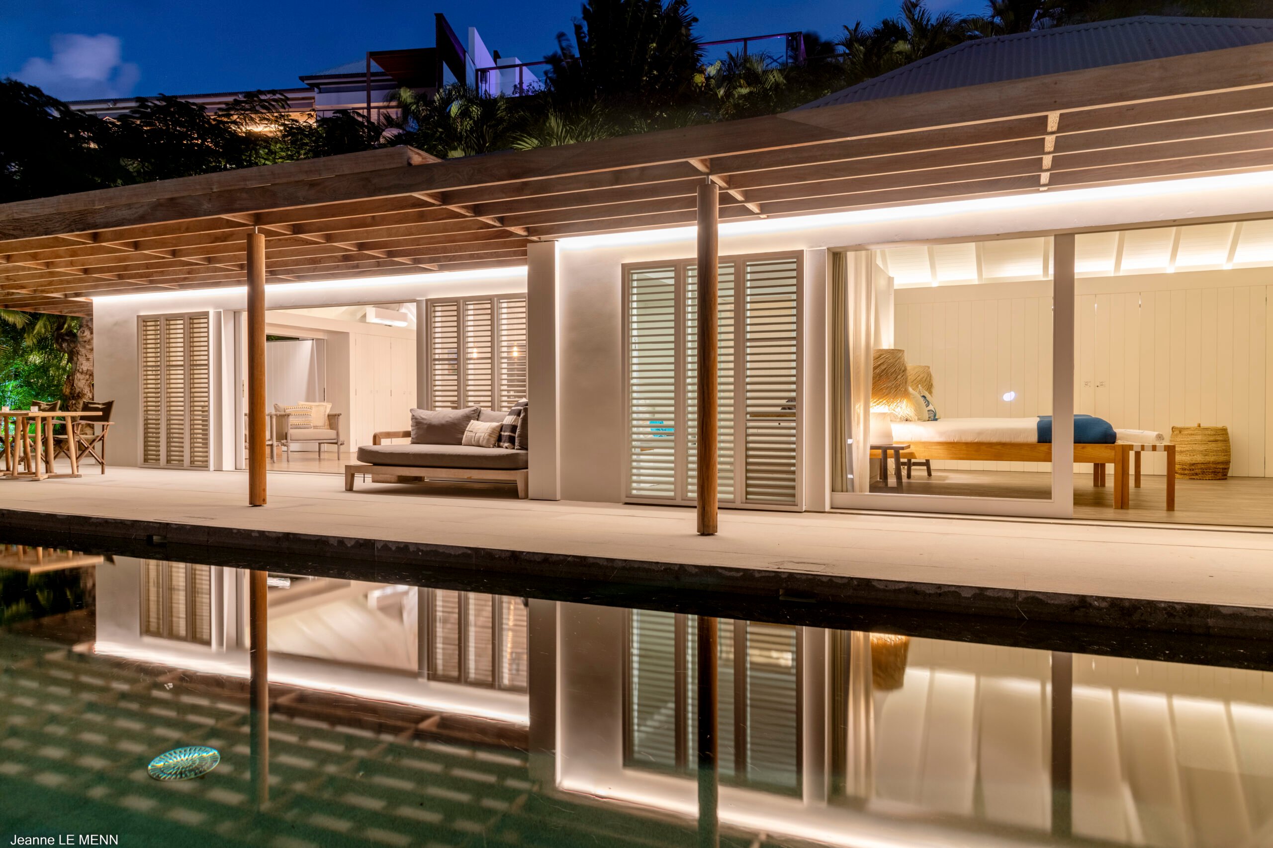 Elegant St Barts villa with poolside terrace illuminated by soft evening lights.