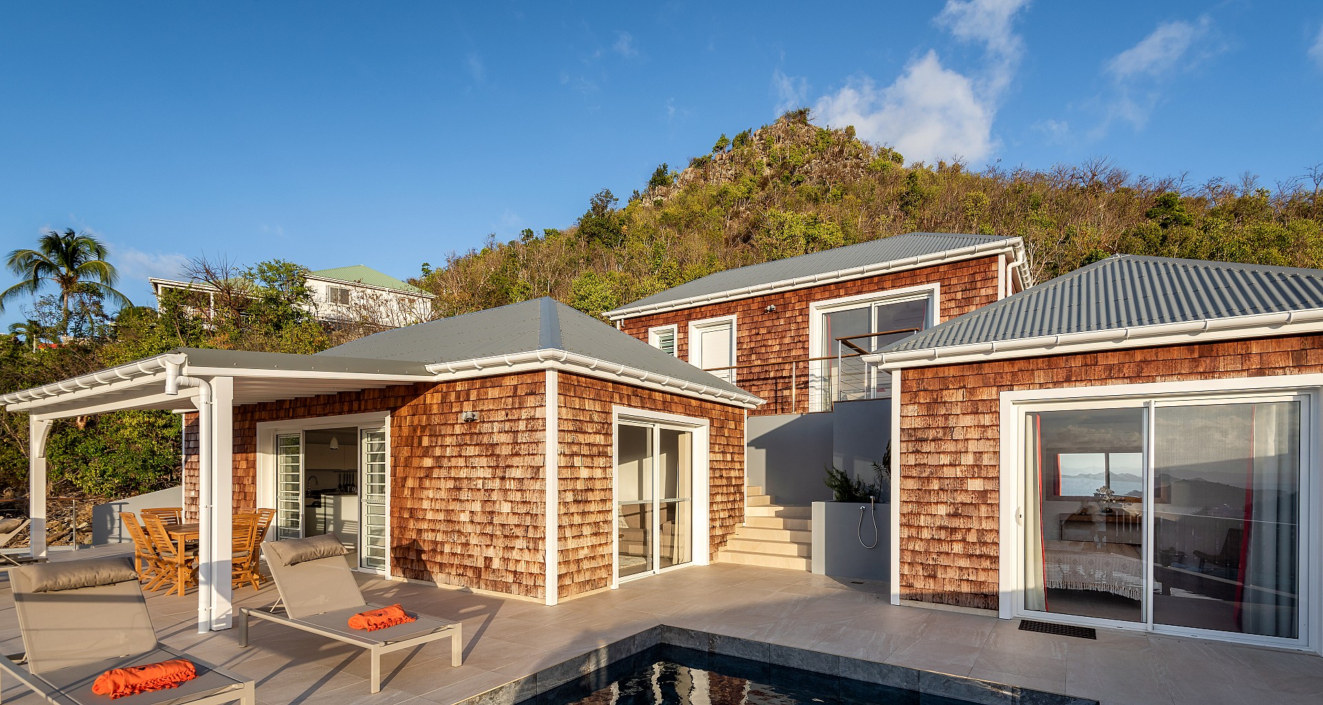 Contemporary villa with cedar-shingle facades, sun loungers, and poolside terrace in St Barts vacation rental.