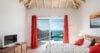 Villa bedroom with red curtains, ocean-view terrace, and vaulted ceiling in St Barts vacation rental.