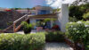 Contemporary St Barts villa exterior with potted plants, shaded terrace, and lush tropical garden.