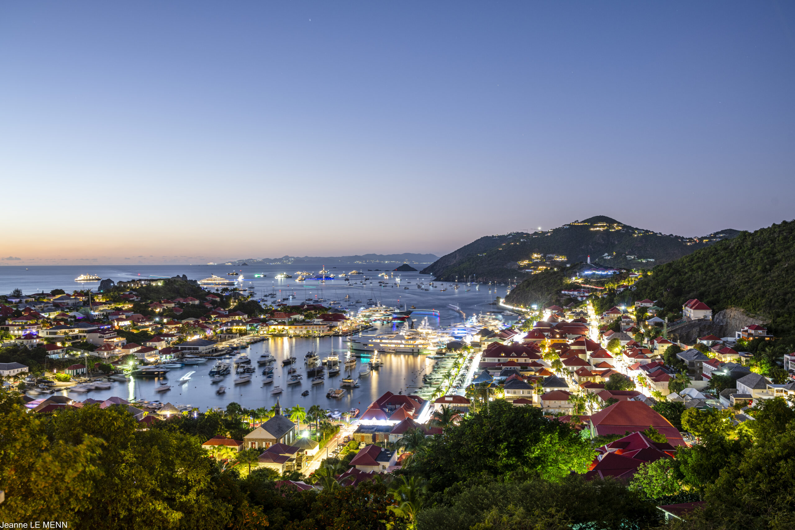 Twilight view from Villa Serenity in St Barts, overlooking Gustavia harbor with yachts, glowing lights, and the Caribbean horizon.