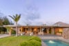 Elegant St Barts villa exterior with garden lawn, pool, and open terrace at sunset