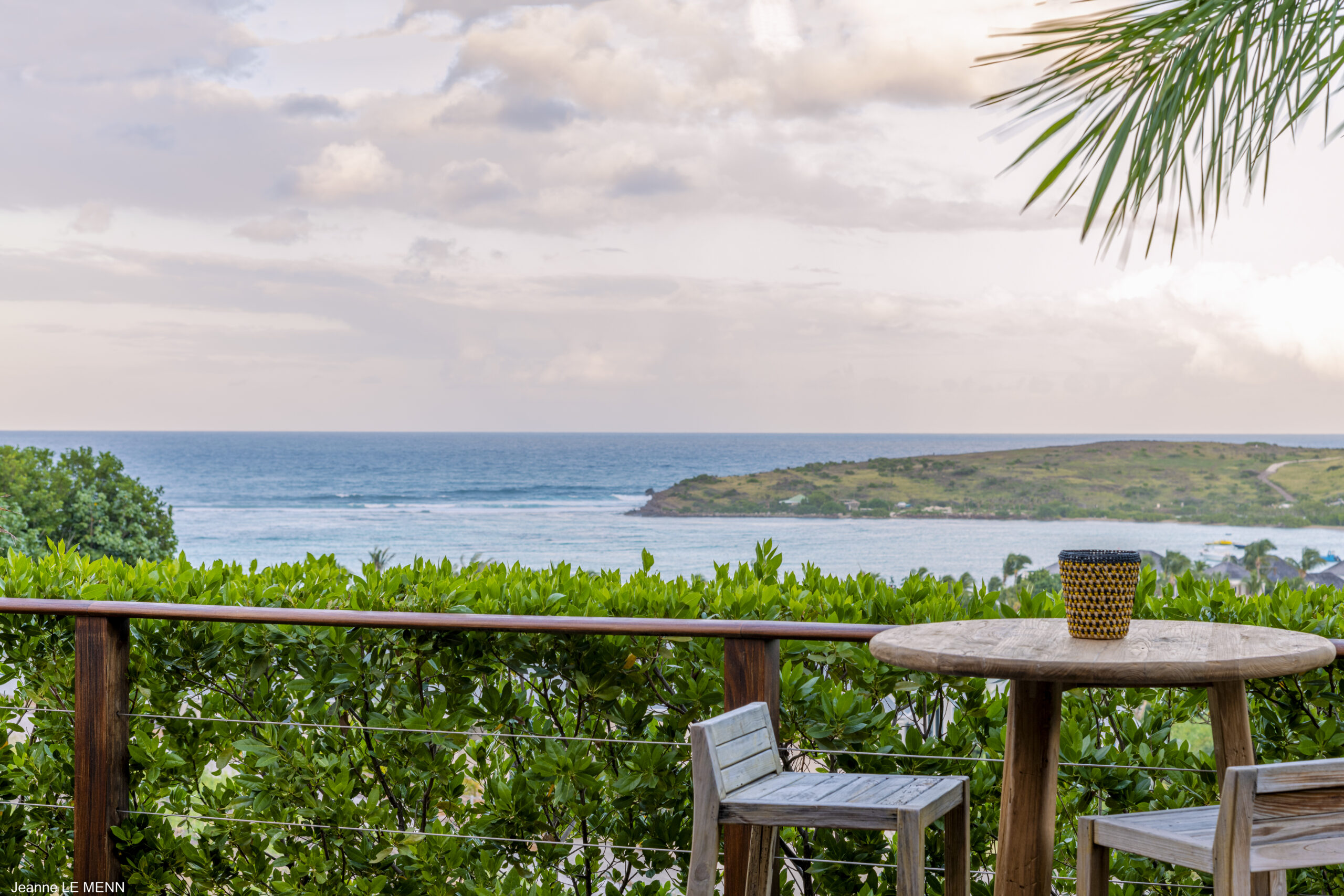 Terrace table with ocean view overlooking lush greenery and offshore island in a St Barts villa rental.