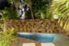 Intimate night pool with stone wall, tropical palms, and loungers in a secluded St Barts villa rental.