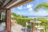 Wooden terrace with bistro table and ocean view surrounded by lush palms at a St Barts villa rental.