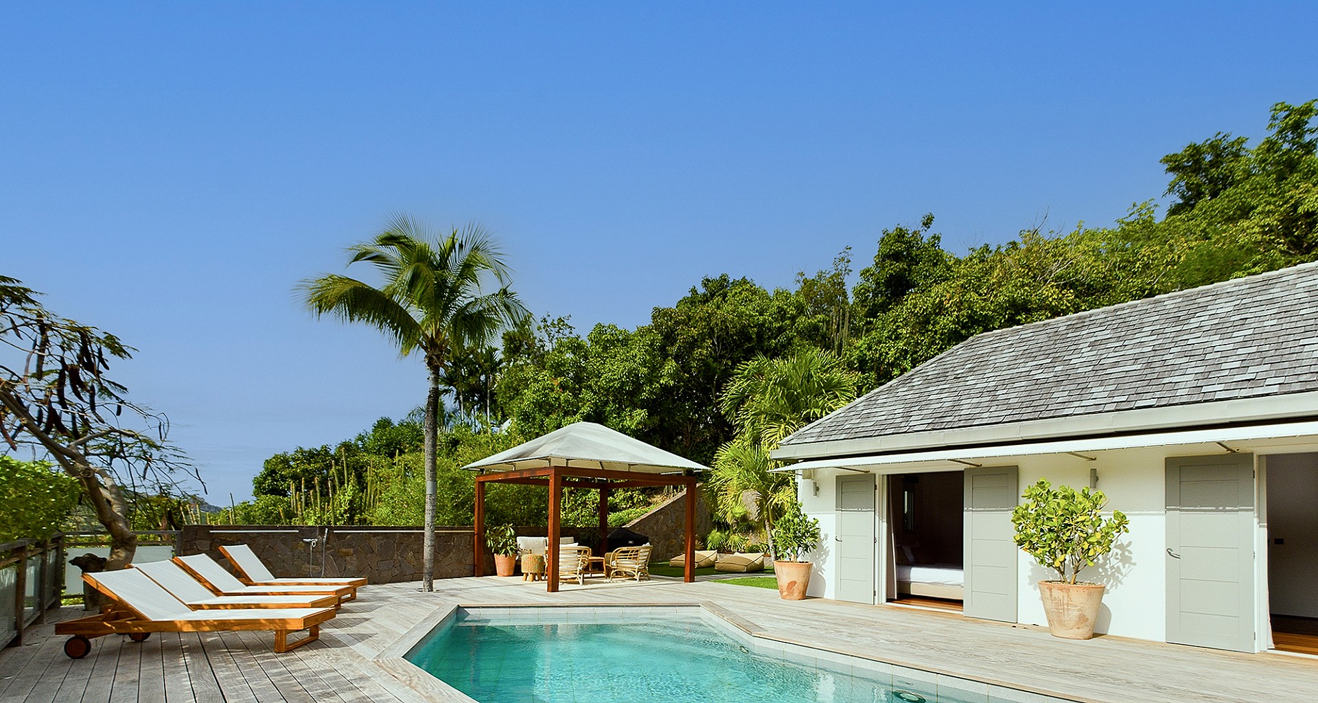 Serene pool terrace at a St Barts villa rental with shaded cabana and sun loungers.
