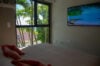Cozy villa bedroom with large window framed by tropical palms and flat-screen TV in St Barts vacation rental