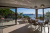 Modern villa dining area with floor-to-ceiling glass doors opening to terrace and ocean views of Gustavia harbor in St Barts rental