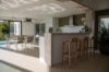 Open-plan villa kitchen with breakfast bar and dining table opening to terrace and pool at luxury St Barts rental