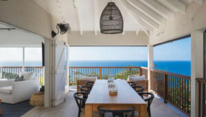 Open-air dining terrace at Villa 3H with wooden table and panoramic ocean views.