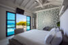 Bedroom with stone accent wall and terrace opening to pool at St Barts villa rental.