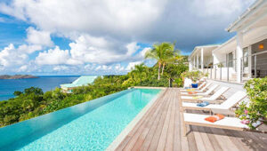 Luxury villa in St. Jean, St. Barts with infinity pool, sun loungers, ocean views, and tropical surroundings.