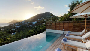 Sunset view from villa pool overlooking lush hills and ocean in Toiny, St. Barts.
