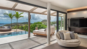 Living room with sliding doors opening to pool terrace and ocean views.