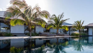 Modern villa with palm trees reflected in a calm pool, Pointe Milou.