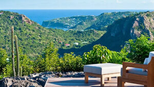 Lounge chair on terrace overlooking lush green hills and ocean view in Gouverneur, St. Barts.