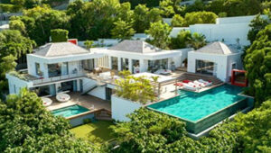 Modern luxury villa with multiple pools surrounded by lush greenery.