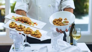 Private chef serving gourmet appetizers and fried dishes at a luxury villa dining setup