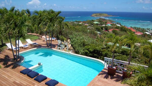 Luxury villa infinity pool overlooking the turquoise Caribbean sea and lush tropical landscape in St. Barts.