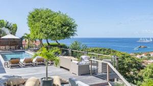 Ocean view from a terrace with a pool, lounge chairs, and outdoor seating in Gustavia
