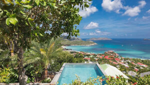 Lush villa view with private pool overlooking the turquoise waters and rooftops of St. Jean Bay.