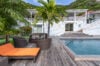 Poolside deck with lounge chairs, palm tree, and white villa exterior at St Barts vacation rental.