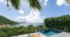 Private infinity pool with sun loungers overlooking Corossol Bay in St Barts, surrounded by lush greenery and views of yachts anchored in the Caribbean Sea