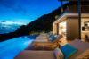 Twilight view of infinity pool villa with cushioned sun loungers and hillside backdrop in St Barts luxury vacation rental