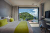 Modern villa bedroom with king bed, lime green accents, and floor-to-ceiling window overlooking hillside in St Barts luxury rental