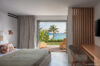 Serene bedroom at St Barts villa rental with ocean-view terrace, natural wood accents, and soft neutral décor