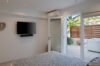 Bright bedroom in a St Barts villa with TV, terrace access, and views of tropical garden and jacuzzi area