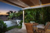 Intimate terrace at a St Barts villa with wooden dining set, lush tropical garden, and twilight ocean view