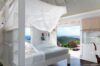 Canopy bed with ocean-view terrace at a bright St Barts vacation rental villa.