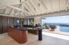 Modern kitchen with island and open terrace overlooking infinity pool and sea at St Barts villa rental