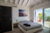 Bedroom with striped bedding, vaulted ceiling, and sliding doors opening to terrace at St Barts villa rental.