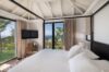 Bedroom with canopy bed, vaulted ceiling, and ocean view through sliding doors at St Barts villa rental.
