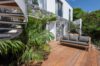 Wooden deck with modern sofa and stone façade surrounded by tropical plants at St Barts private villa rental.