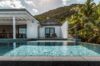 Infinity-edge pool at a luxury St Barts villa with tropical palm trees, modern white architecture, and hillside views