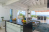 Kitchen island in St Barts villa opening to living room and terrace with sea view.
