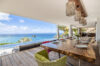 Oceanview villa dining terrace with rustic wooden table, pendant lighting, and infinity pool in St Barts luxury rental