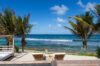 Beachfront terrace with sun loungers and palm trees overlooking turquoise sea at private villa rental in St Barthélemy