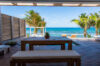 Covered terrace with wooden dining table and ocean view at beachfront luxury villa rental in St Barths