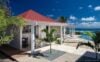Contemporary white villa with red roof, pool terrace, and ocean views in St Barths luxury rentals.