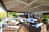 Covered outdoor lounge at luxury st barts villa with wicker furniture and garden view.